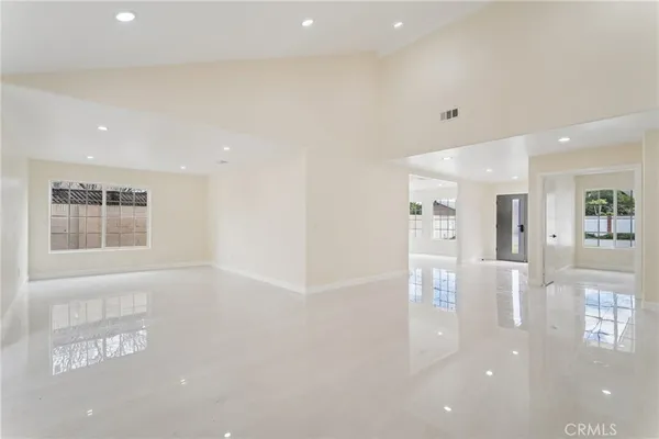 a large white kitchen with stainless steel appliances kitchen island a large counter top and a sink