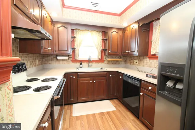a kitchen with a sink a stove cabinets and a wooden floor