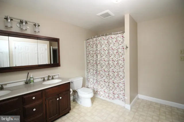 a bathroom with a double vanity sink toilet mirror and shower