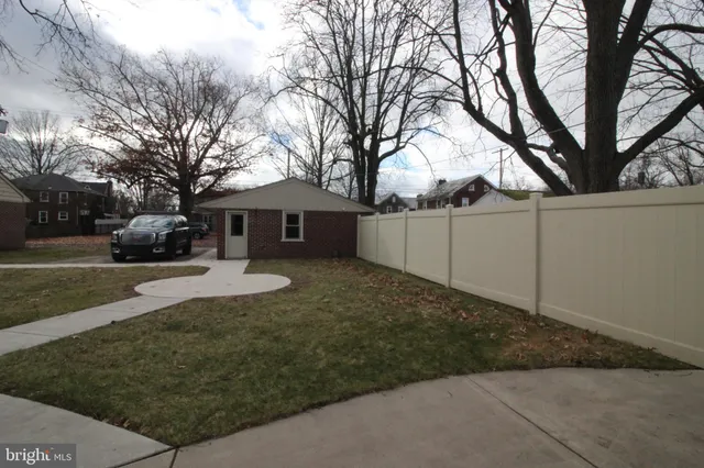 a view of a white house next to a yard with a large tree