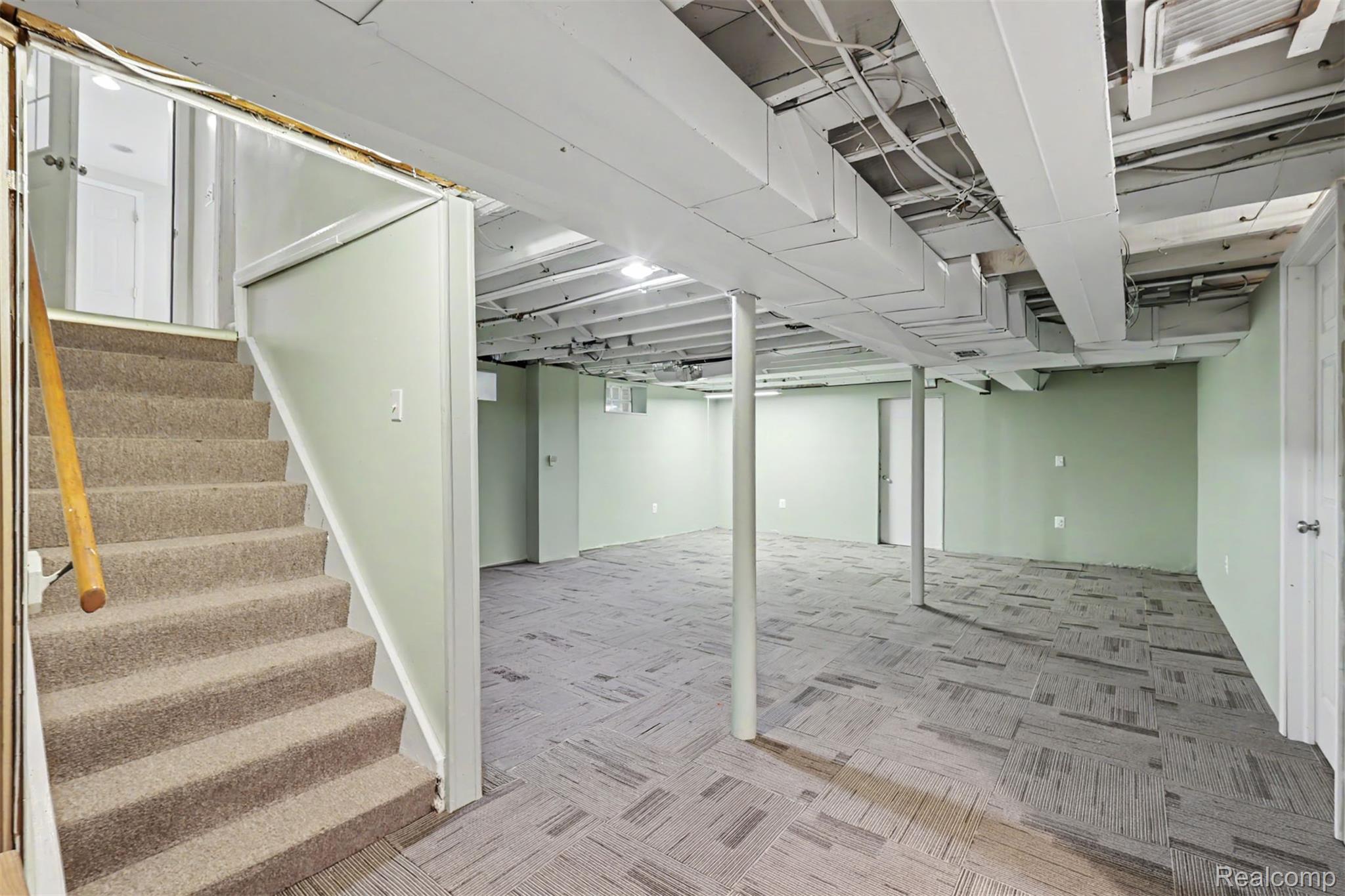 7136 Rosedale Boulevard Allen Park, MI 48101 - Photo 41 of 51 Spacious lower-level area featuring light green walls, exposed white ceiling joists, and patterned gray carpet