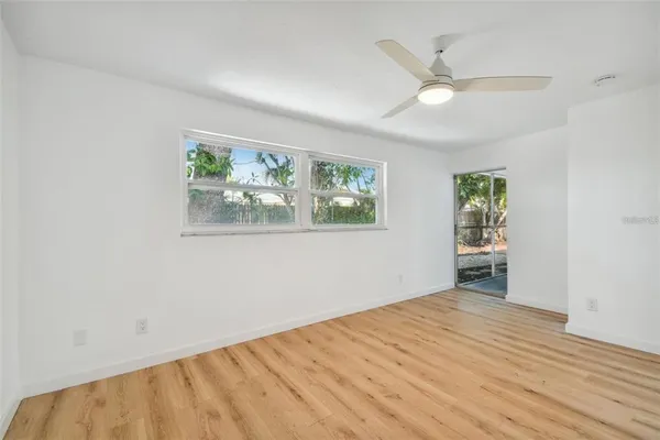 a view of an empty room with wooden floor and a window