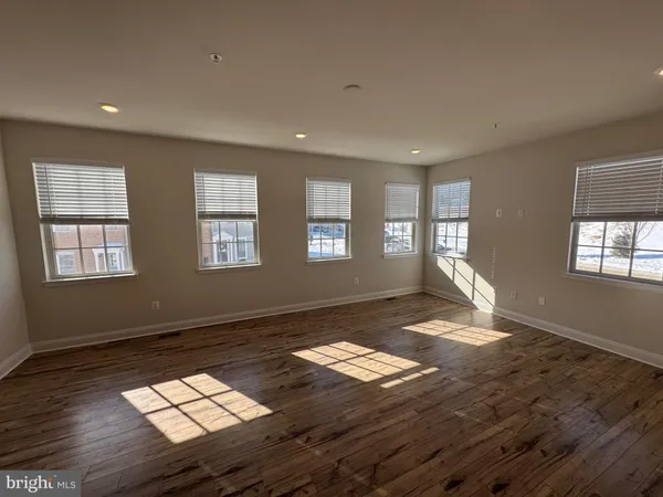 a view of empty room with wooden floor and window