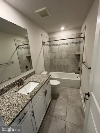 a bathroom with a granite countertop sink a toilet and shower