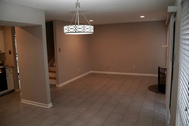 an empty room with wooden floor and chandelier