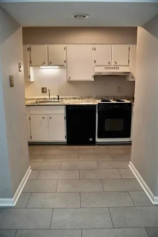 a kitchen with granite countertop a stove and cabinets