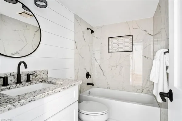 a bathroom with a granite countertop sink a toilet and bathtub
