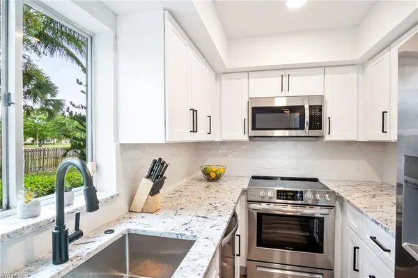 a kitchen with stainless steel appliances granite countertop a stove a sink and a microwave