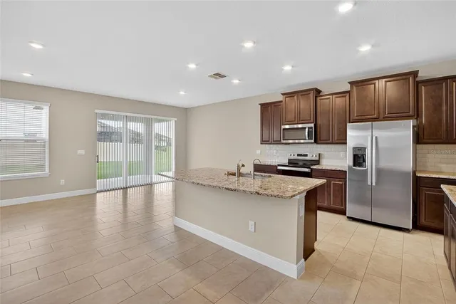 a view of an empty room with a window and a kitchen