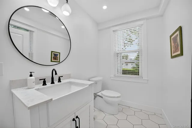 a bathroom with a sink a mirror a toilet and a window