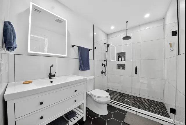 a bathroom with a sink a toilet a mirror and shower