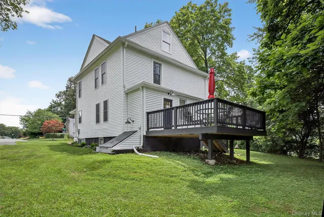 a view of a house with a yard deck and a large tree