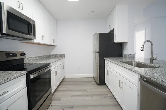 a kitchen with stainless steel appliances granite countertop a stove a sink and a microwave