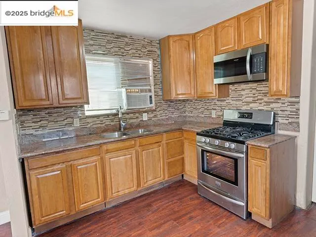 a kitchen with granite countertop a sink stove and microwave