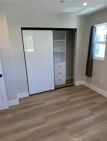 a view of an empty room with wooden floor and closet