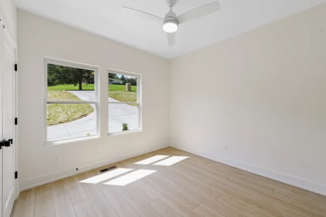 an empty room with wooden floor and windows
