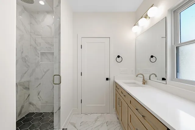 a bathroom with a double vanity sink a large mirror a shower and