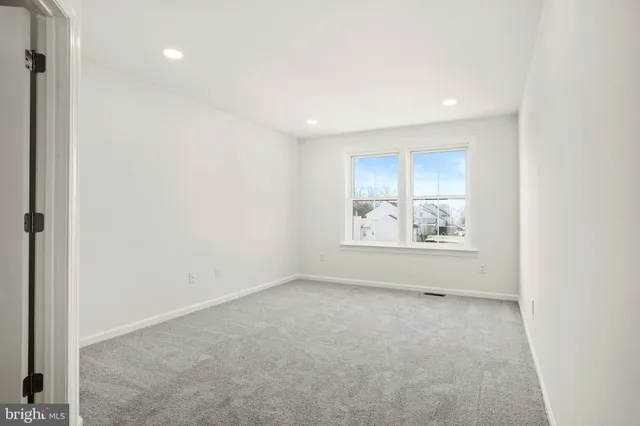 a view of a white house next to a yard with wooden fence