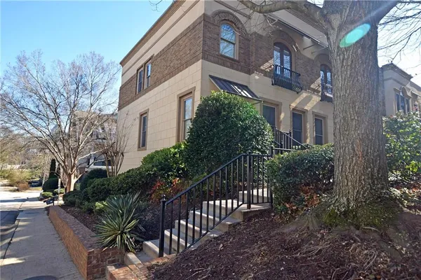 a view of a white building among the street with plants and trees