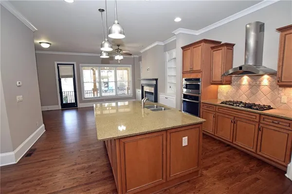 a kitchen with stainless steel appliances granite countertop a sink a stove and a wooden floors