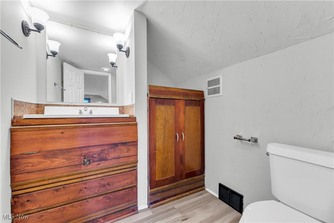 19720 Upper Terrace Road Euclid, OH 44117 - Photo 26 of 31 Bathroom featuring hardwood / wood-style floors, vanity, toilet, and lofted ceiling