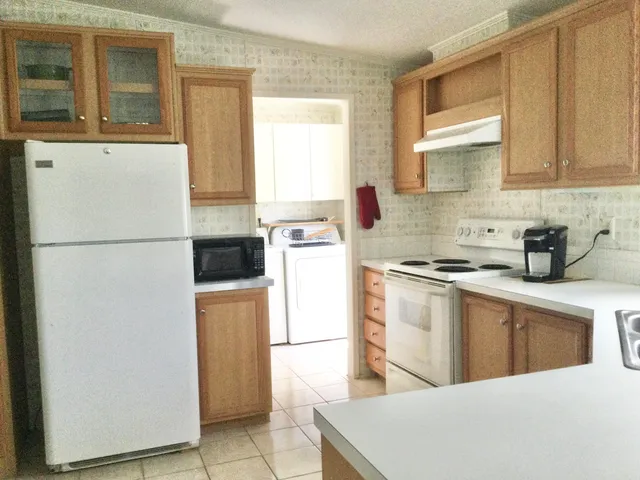 a kitchen with a refrigerator a stove a sink a washer dryer and a window