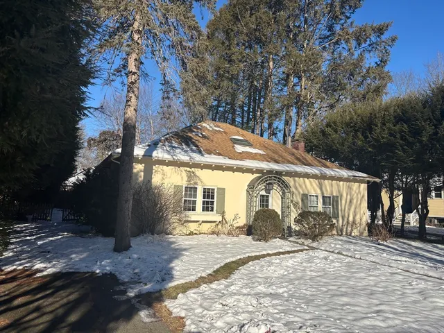a backyard of a house with large trees and outdoor seating