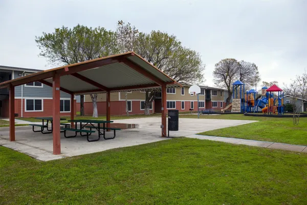 a view of a park with table and chairs under an umbrella