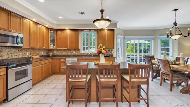 a kitchen with stainless steel appliances granite countertop a stove a sink a stove a dining table and chairs