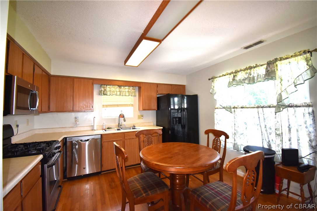 151 Thomas Landing Road Lancaster, VA 22503 - Photo 19 of 39 a kitchen with stainless steel appliances granite countertop a stove a sink dishwasher a dining table and chairs with wooden floor