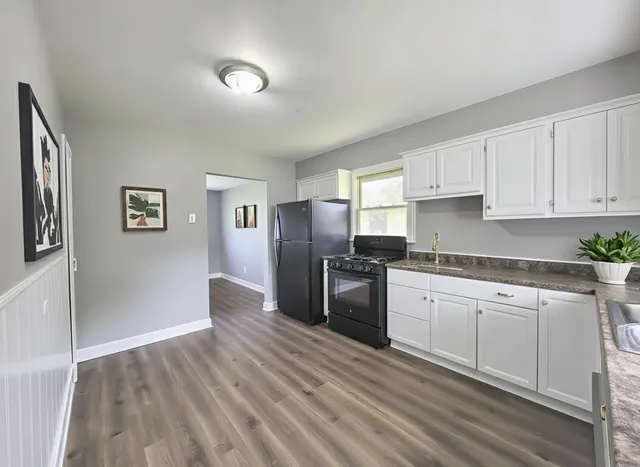 a kitchen with granite countertop a refrigerator stove top oven and cabinets