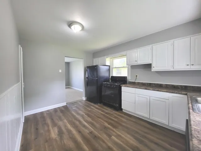 a kitchen with granite countertop a refrigerator and cabinets