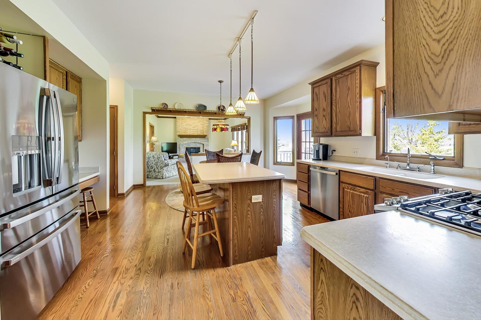 39898 North Harbor Ridge Drive Antioch, IL 60002 - Photo 6 of 27 a kitchen with stainless steel appliances kitchen island granite countertop a stove top oven a sink a dining table and chairs with wooden floor