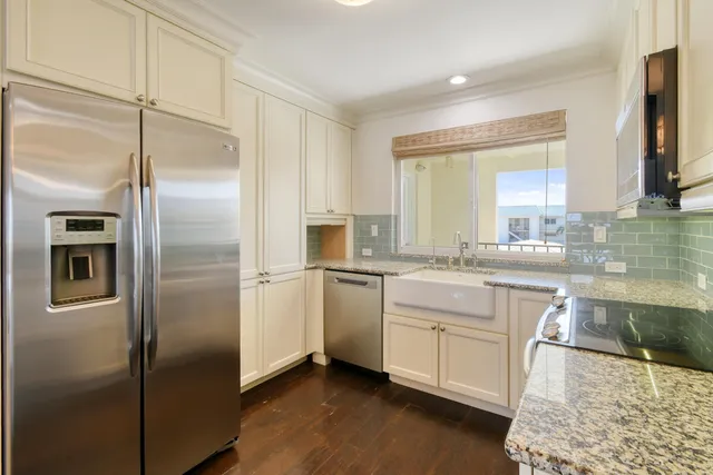 a kitchen with granite countertop white cabinets and stainless steel appliances