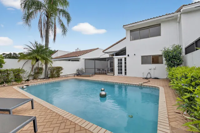 a front view of a house with a garden and palm trees