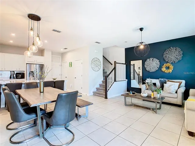 a living room with furniture a dining table and a chandelier