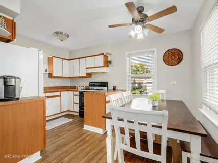 a kitchen with stainless steel appliances granite countertop a stove top oven a sink a dining table and chairs with wooden floor