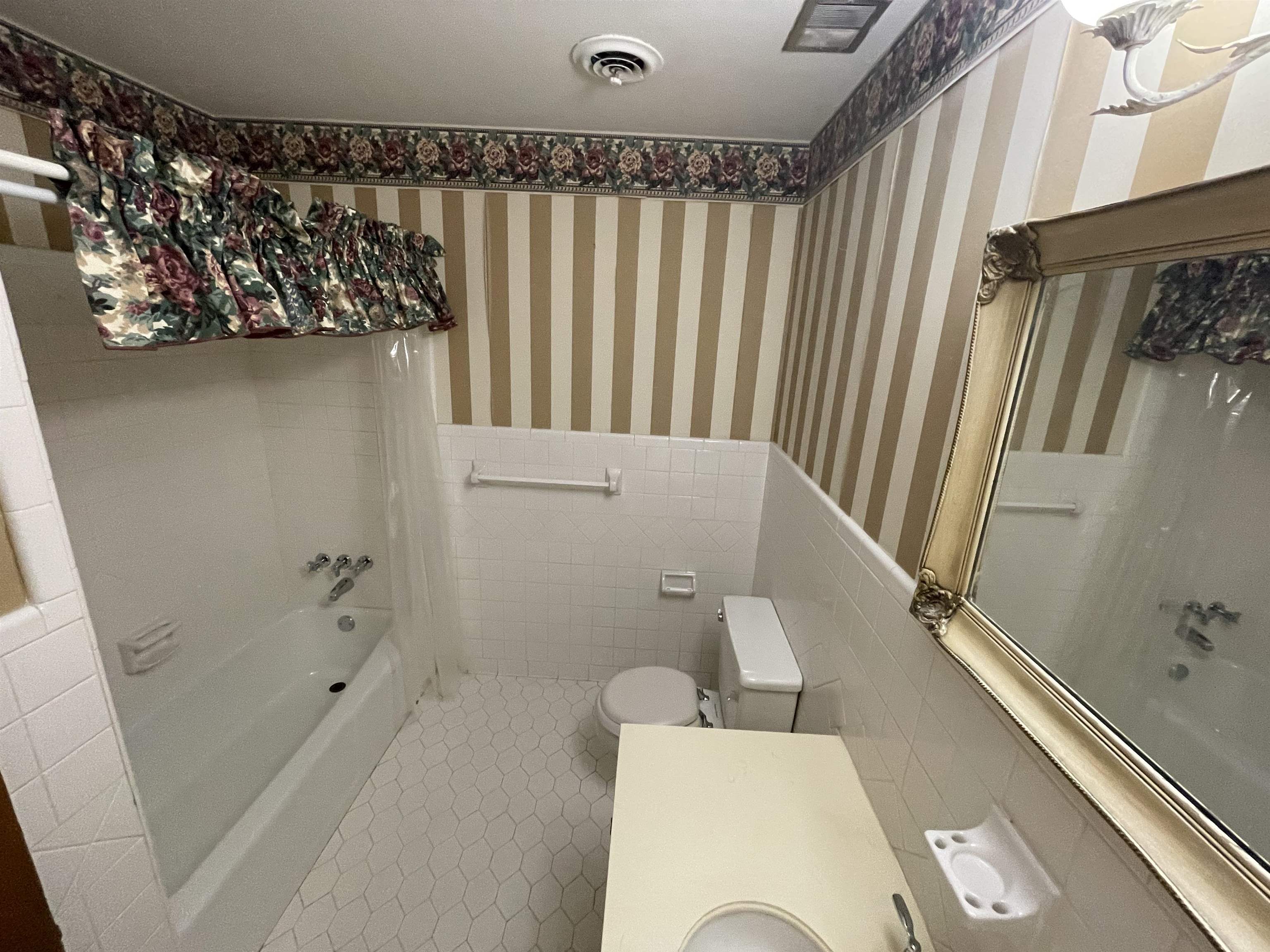 379 McElroy Road Memphis, TN 38120 - Photo 13 of 19 Bathroom featuring tile walls, shower / bath combo, wainscoting, tile patterned floors, and vanity