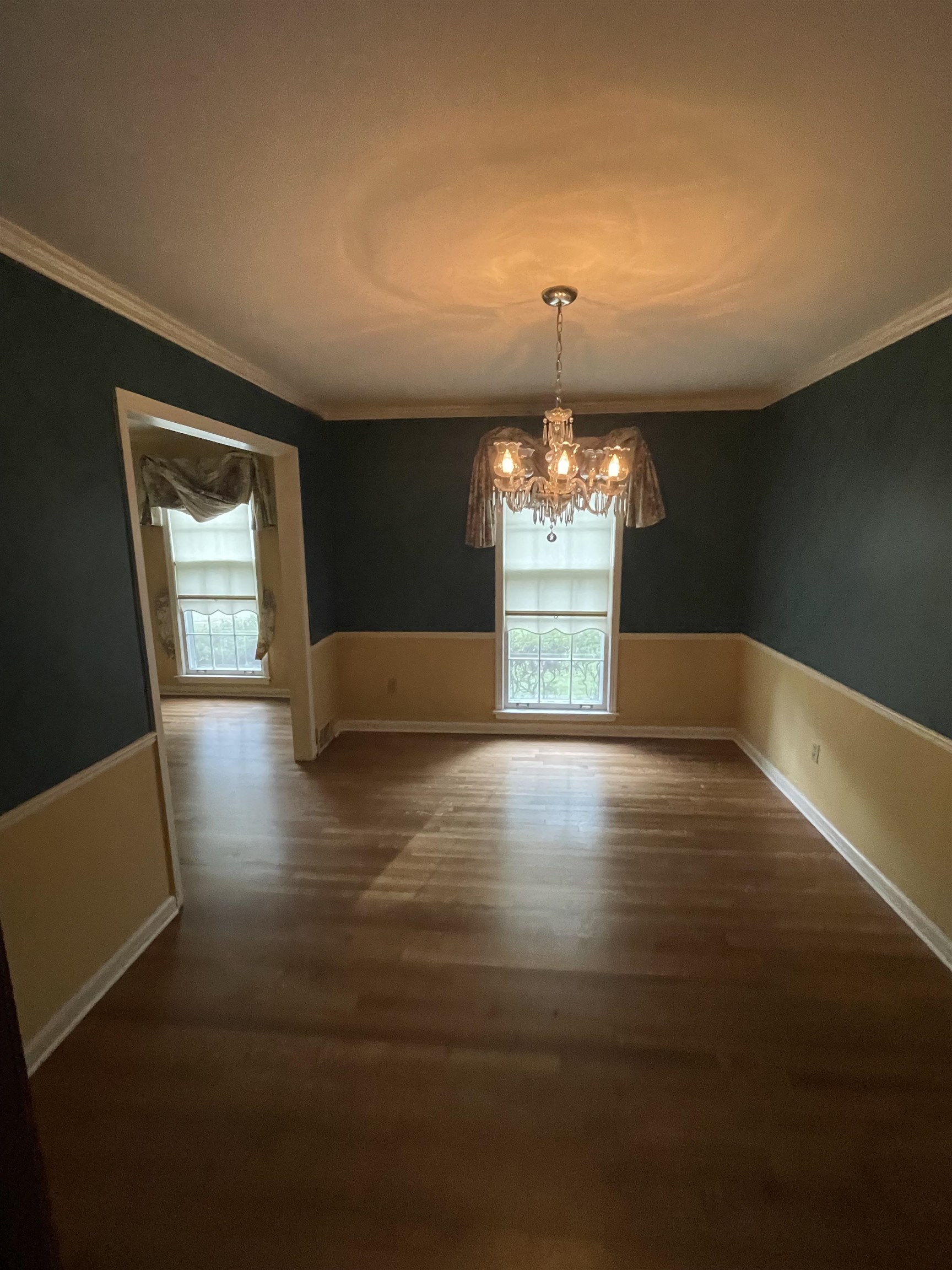 379 McElroy Road Memphis, TN 38120 - Photo 7 of 19 Unfurnished dining area with a wainscoted wall, crown molding, dark wood-style flooring, healthy amount of natural light, and a chandelier