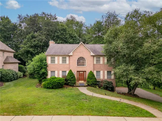 a view of a yard in front of a house with plants and large tree