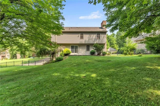 a view of a house next to a big yard and large trees