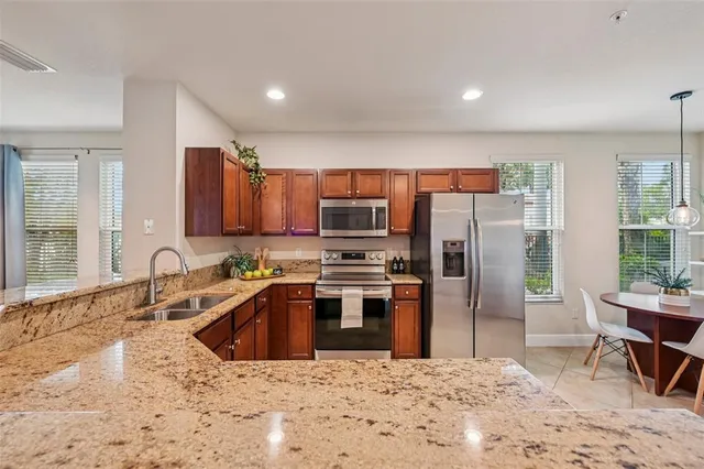 a kitchen with stainless steel appliances kitchen island granite countertop a refrigerator and a sink