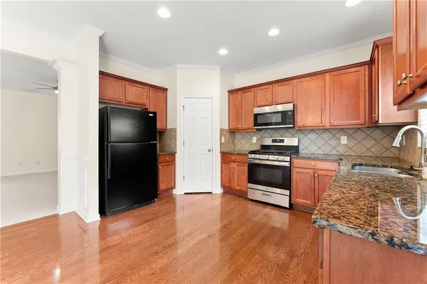 a kitchen with granite countertop a refrigerator and a stove top oven