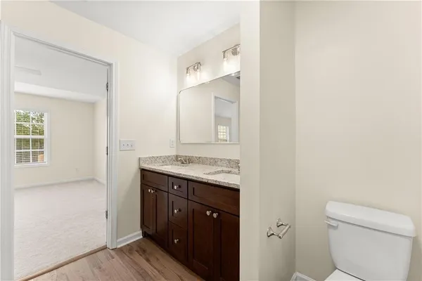 a bathroom with a granite countertop toilet a sink and a mirror