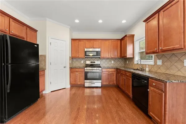 a kitchen with granite countertop a refrigerator and a stove top oven