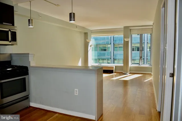 a view of an empty room with wooden floor and a window