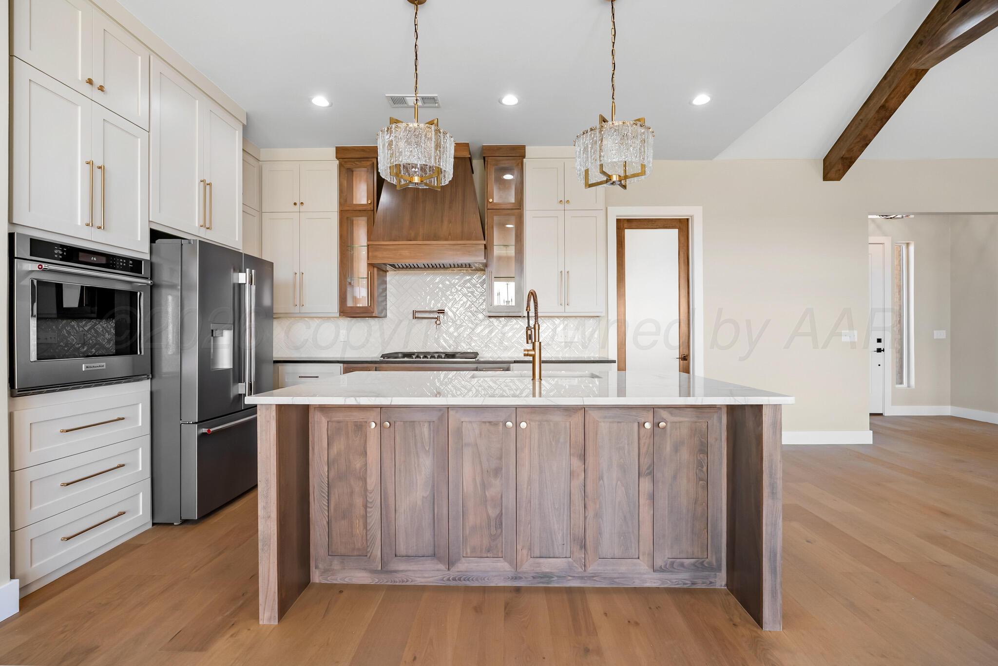 4201 Juniper Springs Road Amarillo, TX 79119 - Photo 7 of 27 a large kitchen with granite countertop a large kitchen island white cabinetry and stainless steel appliances