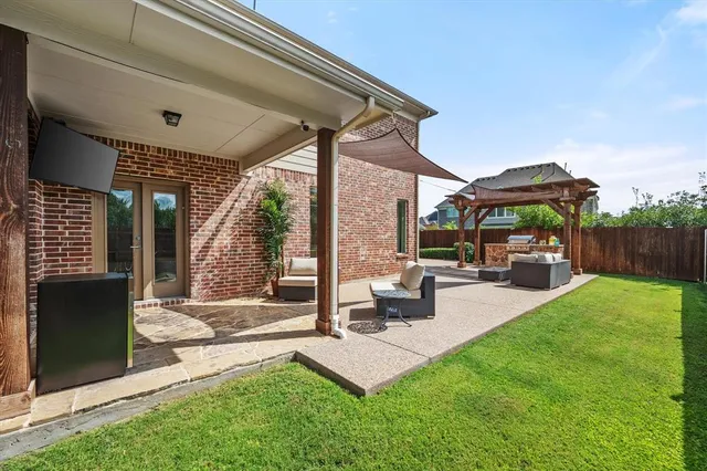 a view of a patio with table and chairs under an umbrella with a small yard
