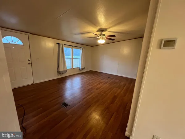 a view of empty room with wooden floor and fan