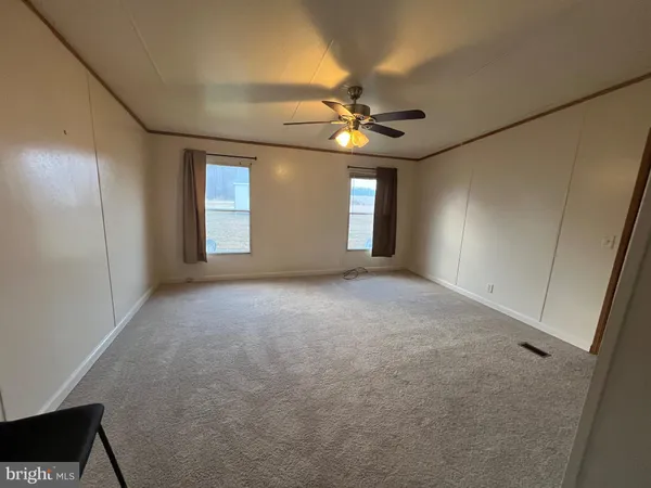 an empty room with windows and fan